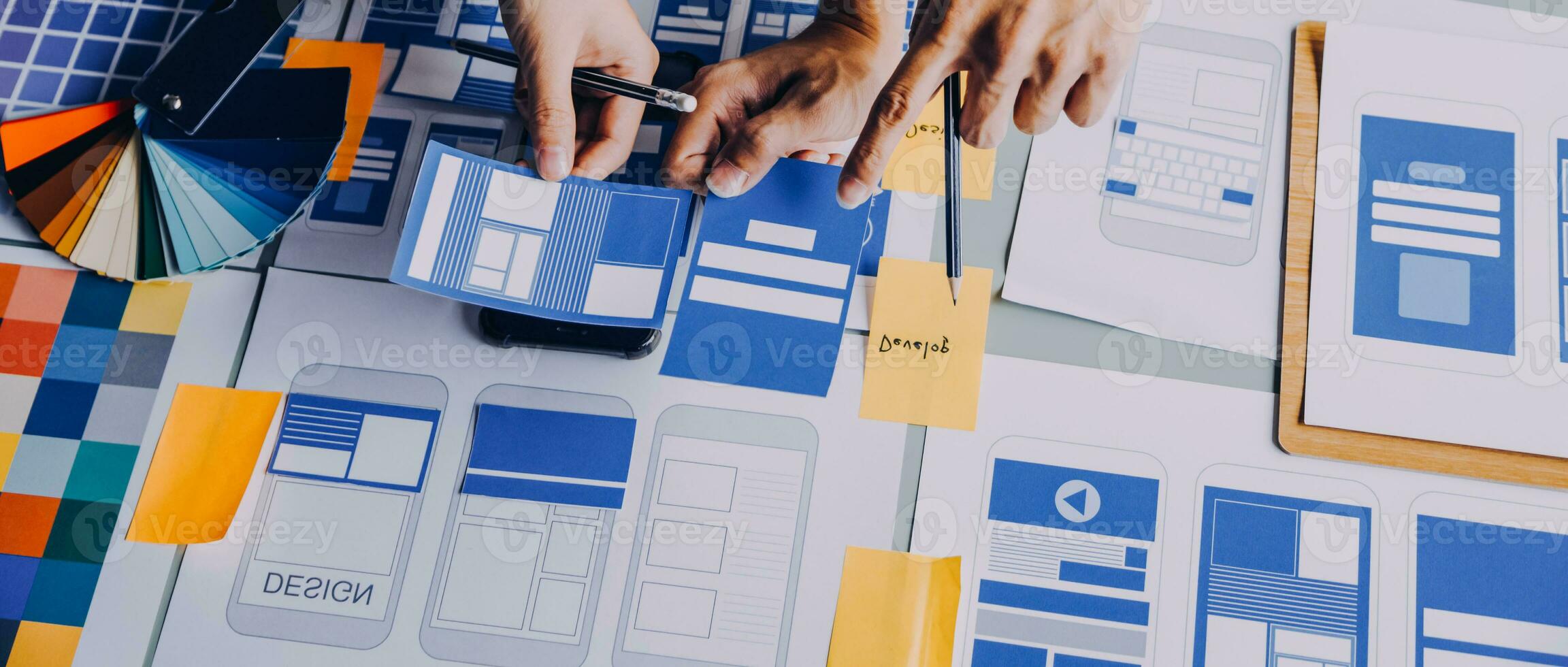 Close up ux developer and ui designer brainstorming about mobile app interface wireframe design on table with customer breif and color code at modern office.Creative digital development agency photo