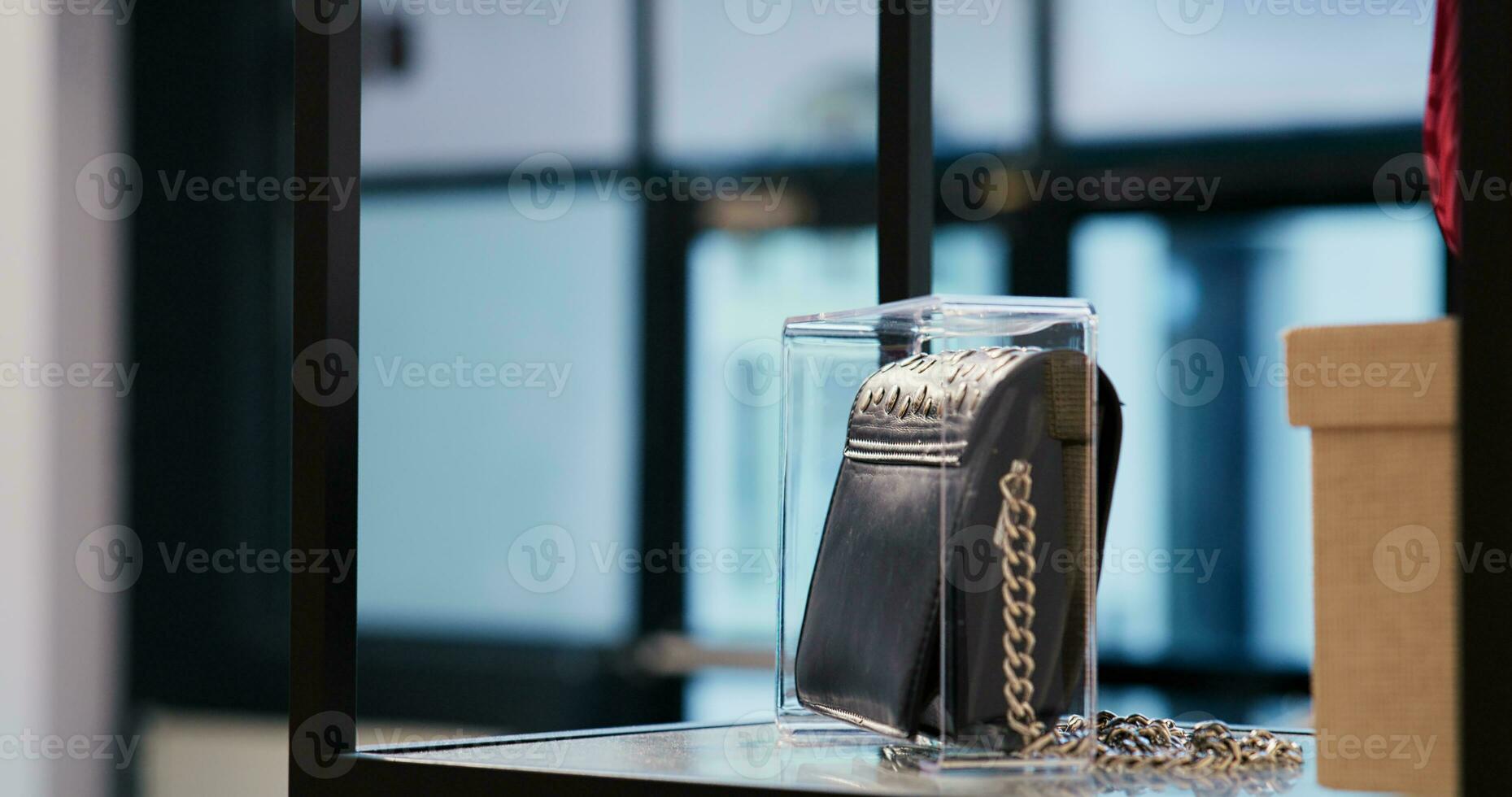 Selective focus of trendy black bag in empty modern boutique, filled with multiple racks with fashionable clothes and trendy accessories. Shopping mall equipped with stylish merchandise photo