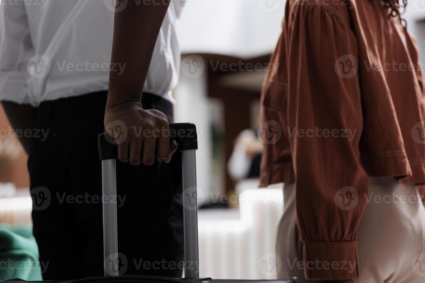 Partners at reception counter in hotel lobby, carrying bags in hallway before doing check in procedure. Young couple arriving at modern resort with room reservation. Close up. photo