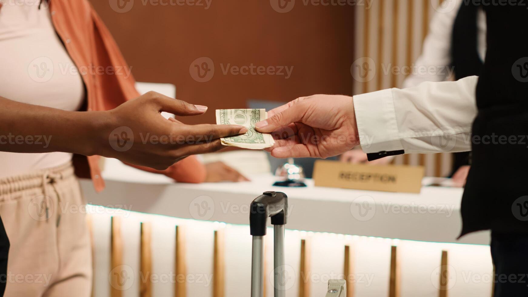 Close up of thankful hotel guest tipping helpful bellboy after receiving great customer service. African american woman handing dollar banknote to porter employee for helping with baggage photo