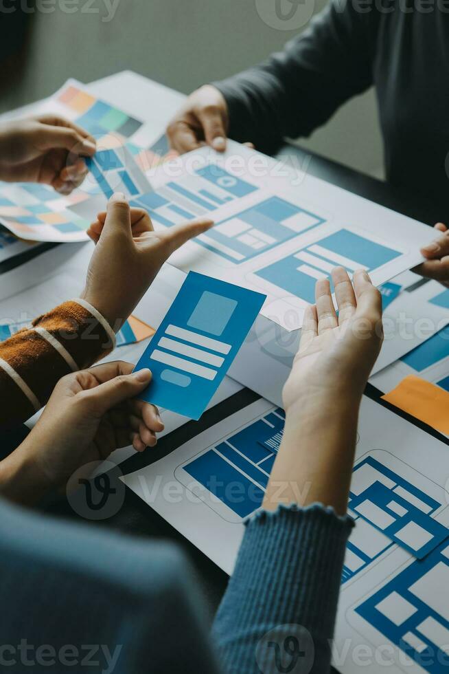 Close up ux developer and ui designer brainstorming about mobile app interface wireframe design on table with customer breif and color code at modern office.Creative digital development agency photo