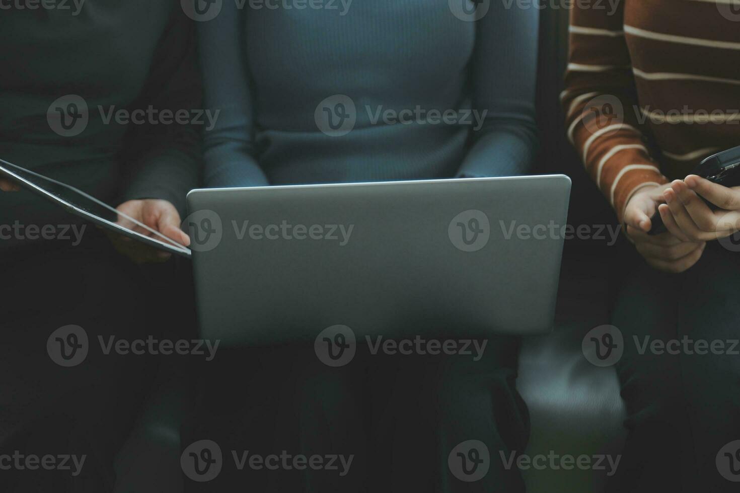 Three beautiful Asian girls using smartphone and laptop, chatting on sofa together at cafe with copy space, modern lifestyle with gadget technology or working woman on casual business concept photo