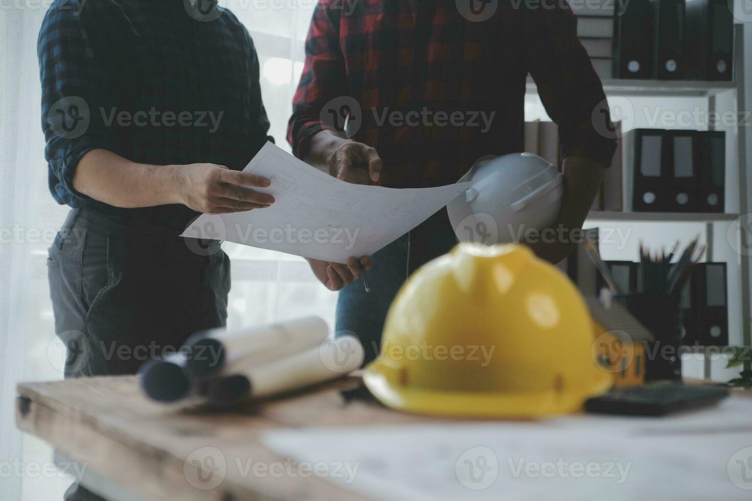 Close up of civil male engineer asian working on blueprint architectural project at construction site at desk in office. photo