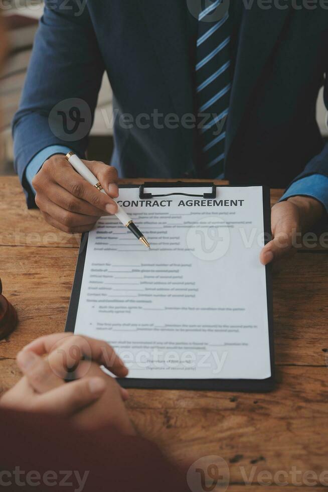 Justice and Law concept. Legal counsel presents to the client a signed contract with gavel and legal law or legal having team meeting at law firm in background photo