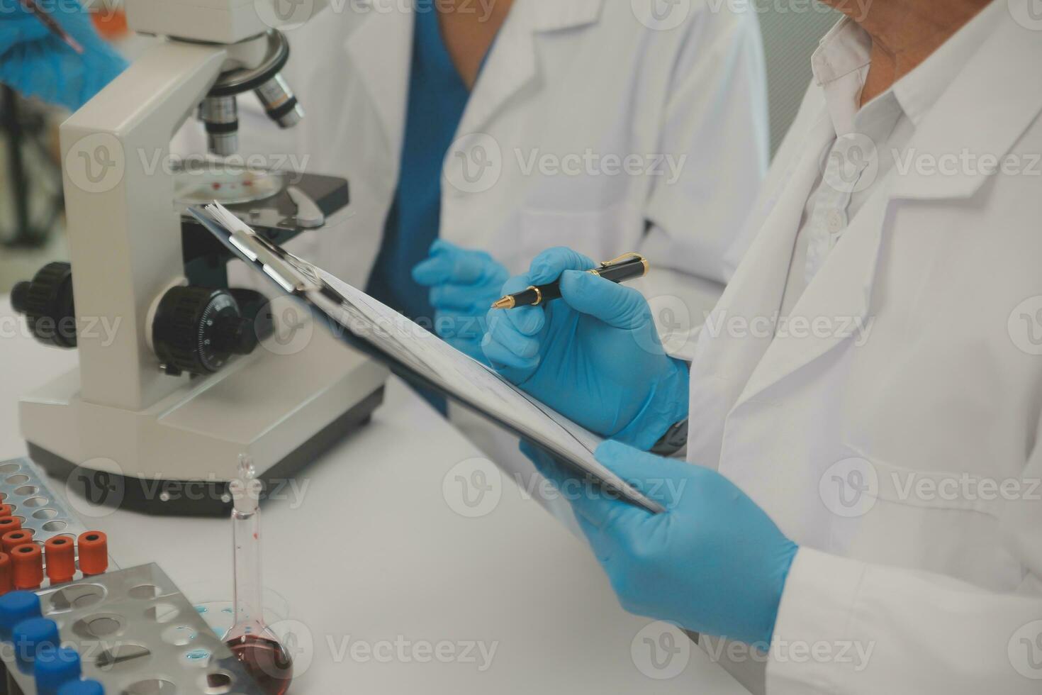 Health care researchers working in life science laboratory. Young female research scientist and senior male supervisor preparing and analyzing microscope slides in research lab. photo