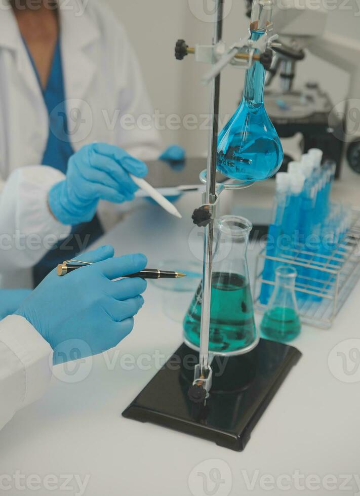 Health care researchers working in life science laboratory. Young female research scientist and senior male supervisor preparing and analyzing microscope slides in research lab. photo