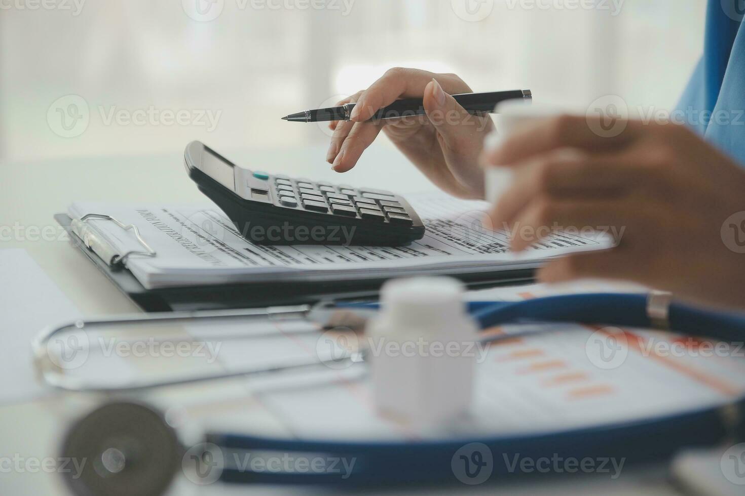 Doctor or physician using calculator and work on laptop computer with medical stethoscope on the desk at clinic or hospital. Medical healthcare costs ,fees and revenue concept. photo