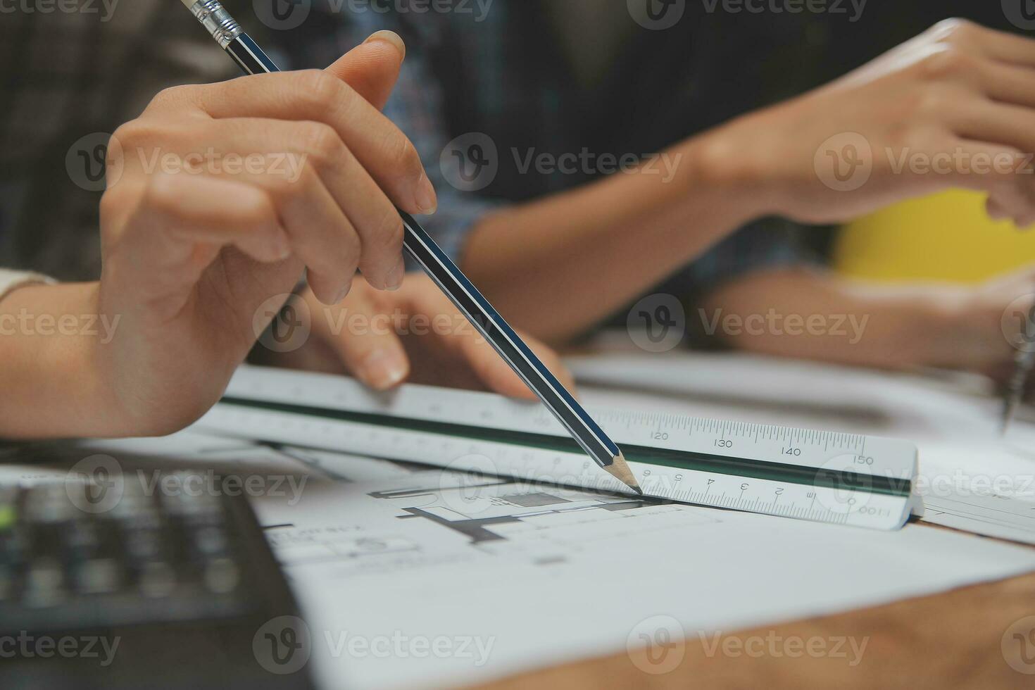 Team of multiethnic architects working on construction plans in meeting room. Engineers discussing on project in office. Mature businessman and woman standing around table working on blueprint. photo