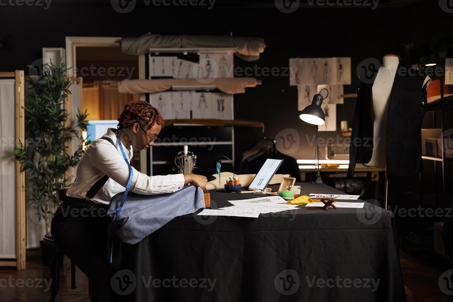 African american seamstress using industrial sew machine to do creative embroidery on piece of fabric to be used on upcoming bespoke fashion collection. Expert tailor working on sartorial collection photo