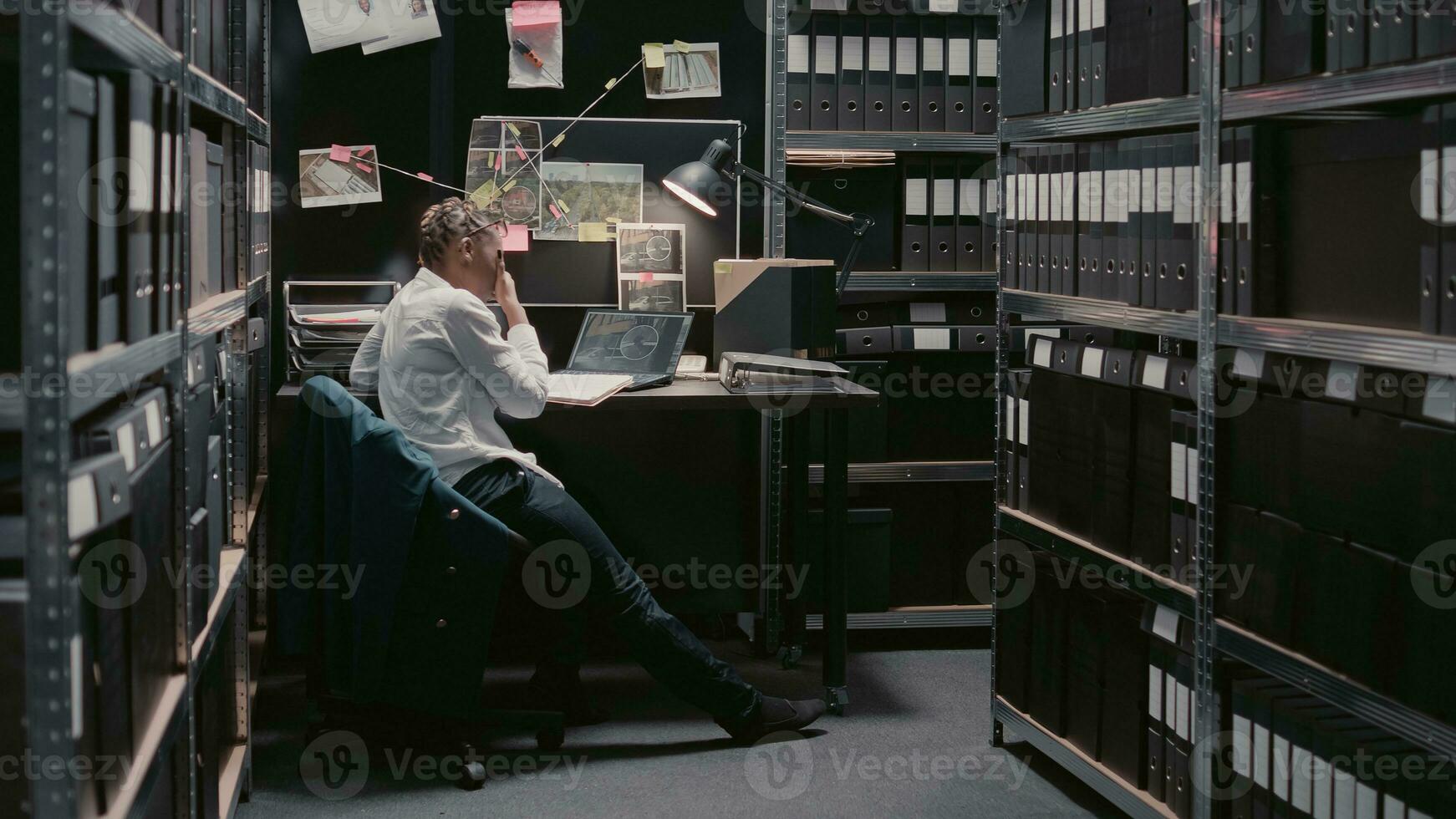 Private officer reading case file information in archive, trying to conduct criminal investigation and catch suspect. Young policewoman reviewing surveillance footage in incident room. photo