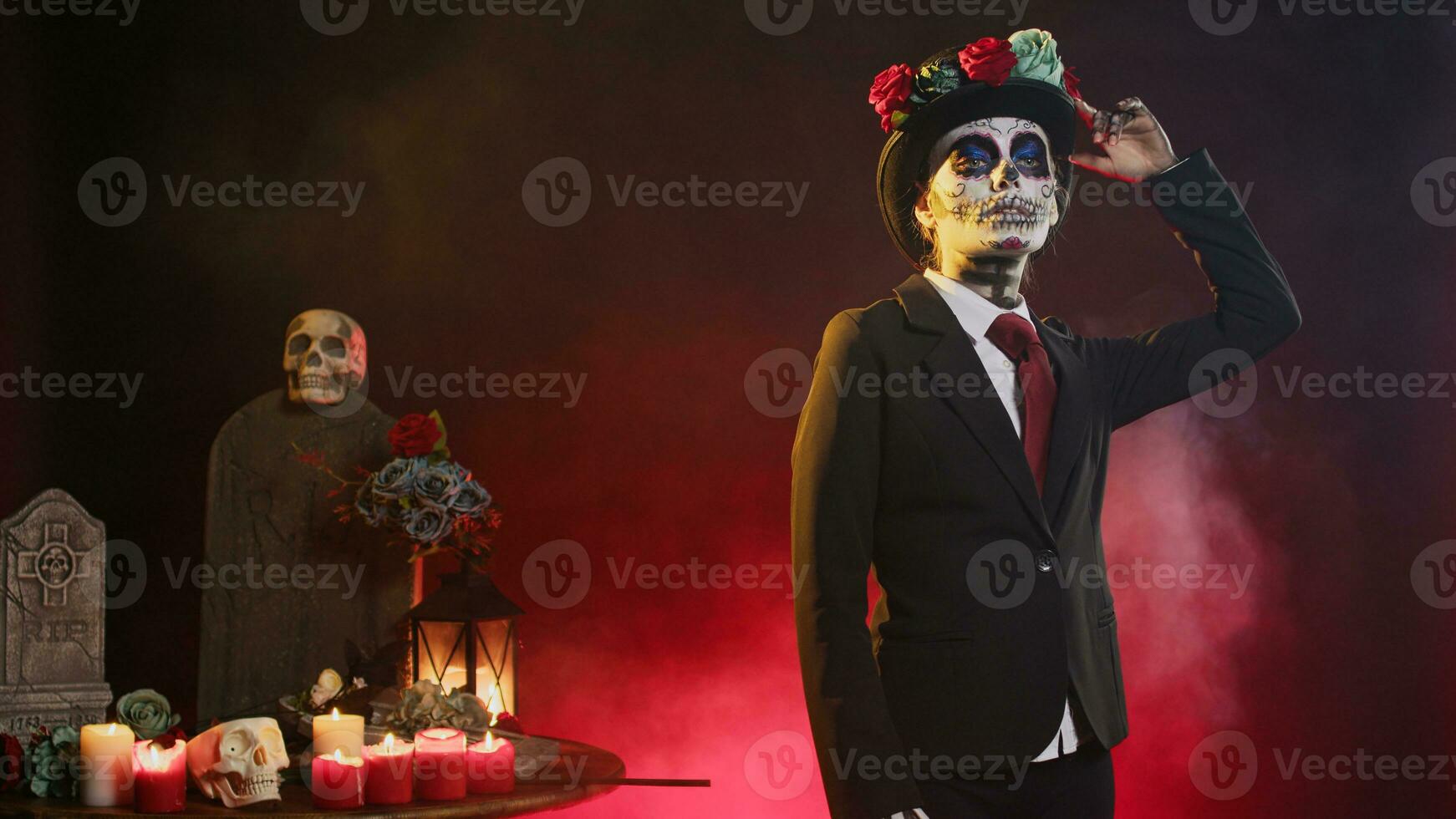 Scary holy entity in halloween costume with skull make up celebrating holy mexican tradition, looking like lady of death. Santa muerte ritual celebration with black and white body art in studio. photo