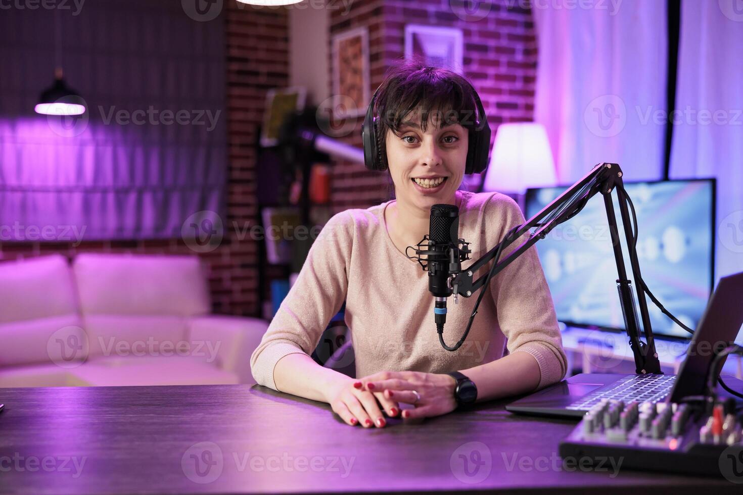 Portrait of cheerful social media influencer filming live show from her home studio, talking to internet channel audience. Content creator recording vlogging episode using modern equipment photo