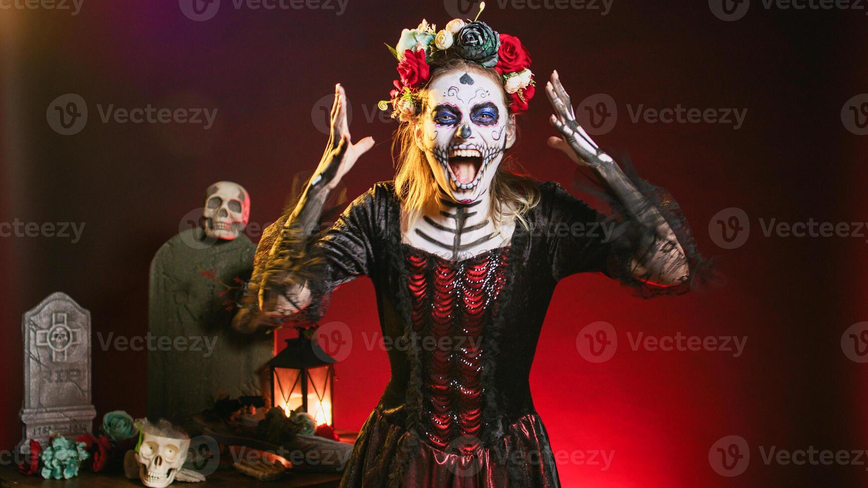 Horror goddess of death yelling in costume with skull body art, wearing flowers crown and screaming like holy santa muerte to celebrate dios de los muertos. Woman on tranditional mexican holiday. photo