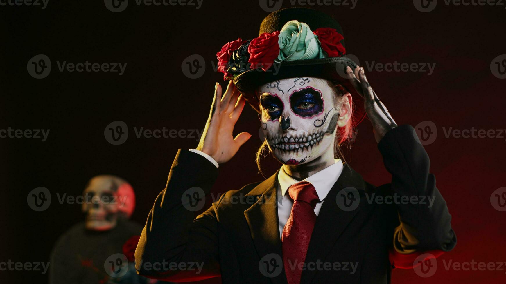 Spooky female model wearing santa muerte costume in studio, having black and white skull make up. Celebrating day of the dead holy mexican tradition, festival body art horror look. Handheld shot. photo