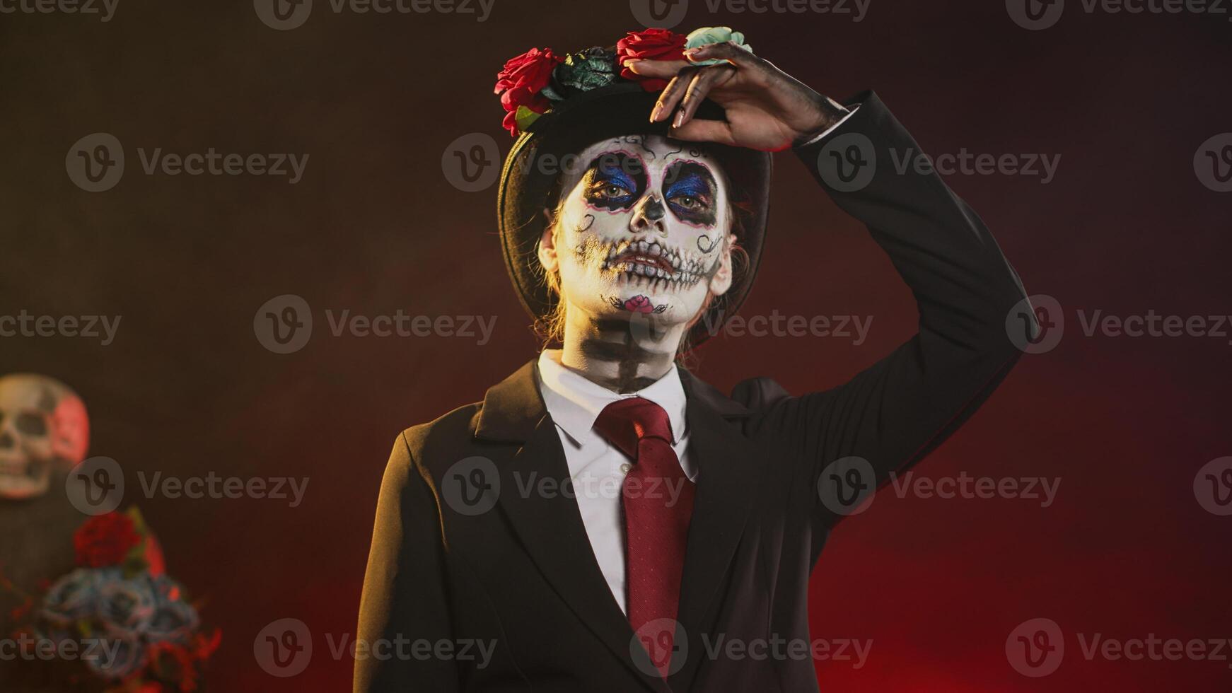 Spooky goddess in halloween costume with skull make up celebrating holy mexican tradition, posing in studio. Looking like lady of death at santa muerte ritual celebration. Handheld shot. photo