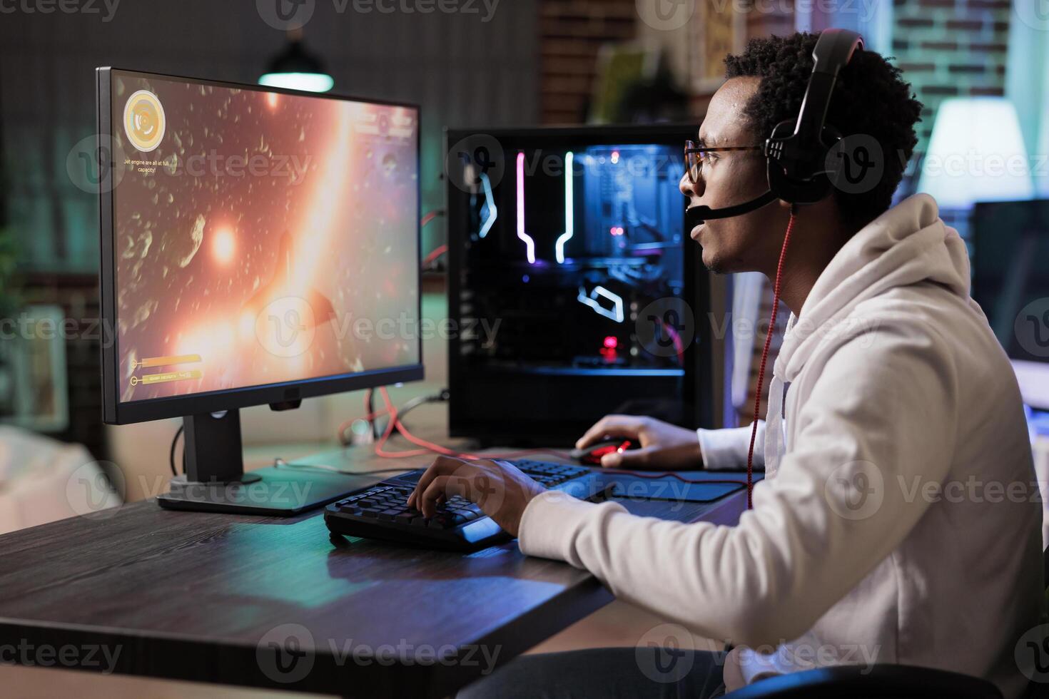 Gamer playing classic arcade spaceship racing videogame, doing flying maneuvres through asteroid clusters. African american man using high tech gaming computer to compete against opponents photo