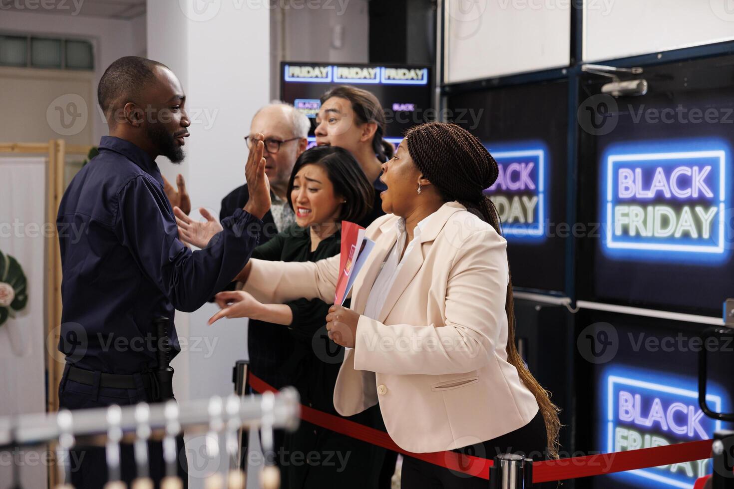 Anxious diverse people wait in line for discounts and deals, standing in behind red tape at clothes shop entrance waiting for opening. Shoppers ready to start Black Friday shopping photo