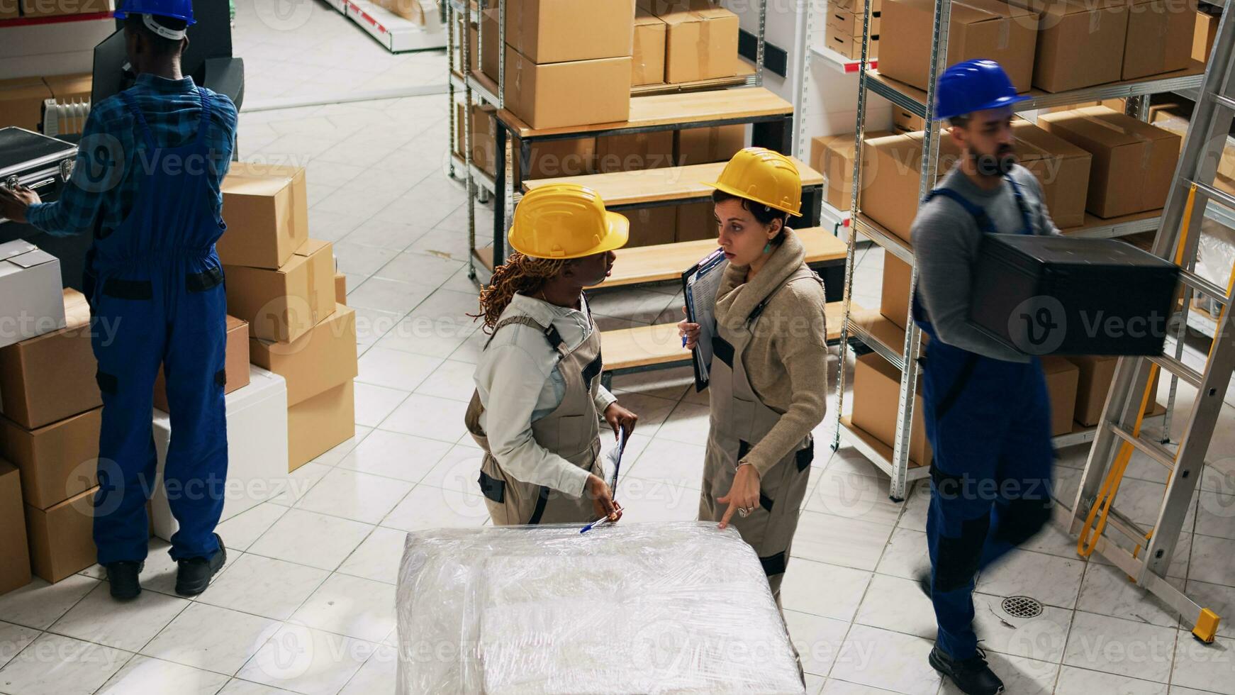 Diverse women talking about shipment and delivery in storage room, analyzing list of stock logistics. Young people working with industrial products and packages of goods, stockroom. Tripod shot. photo