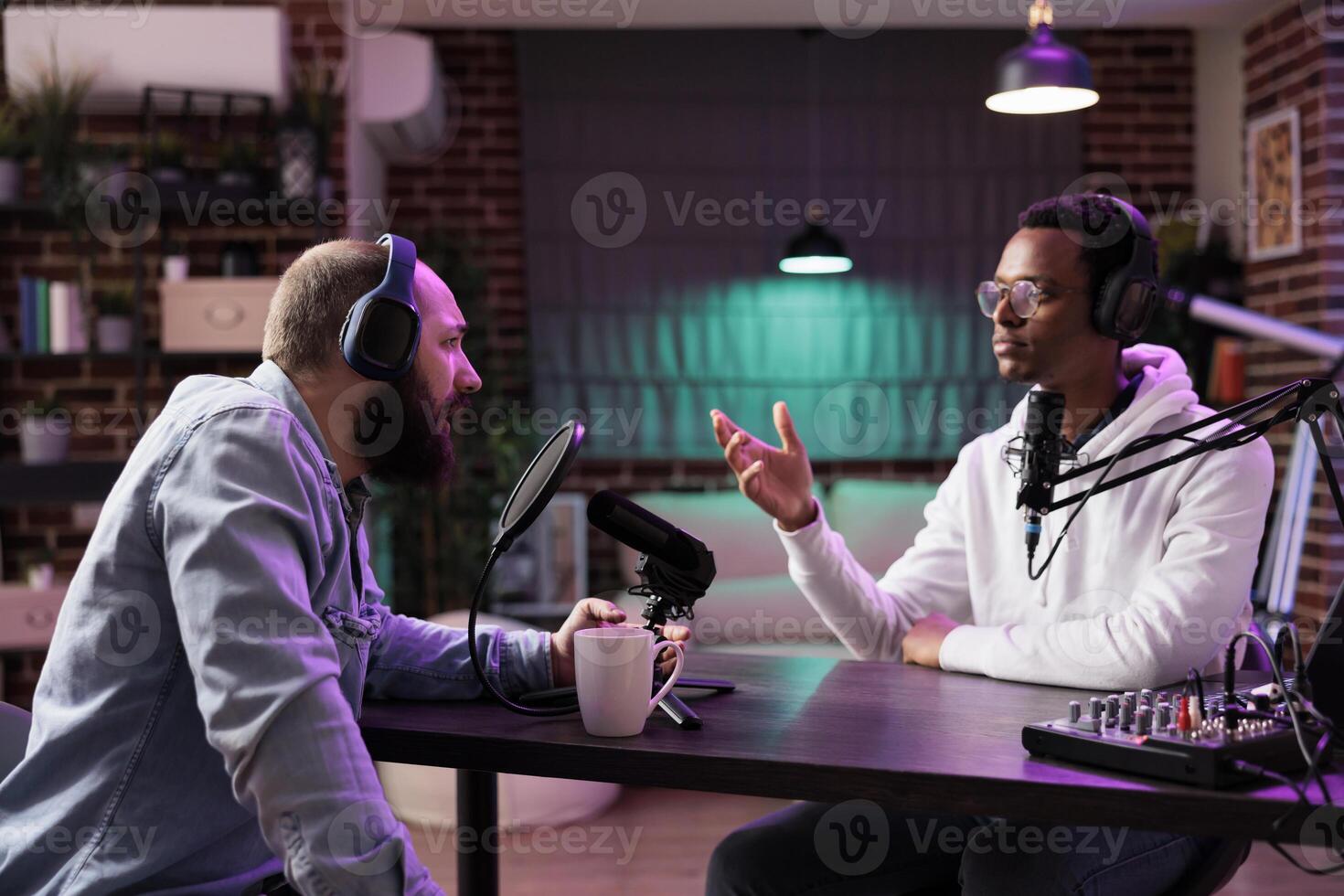 Podcast show host and guest arguing with each other and presenting arguments during online live broadcast in home studio. Men in neon lights decorated living room talking for internet audiences photo