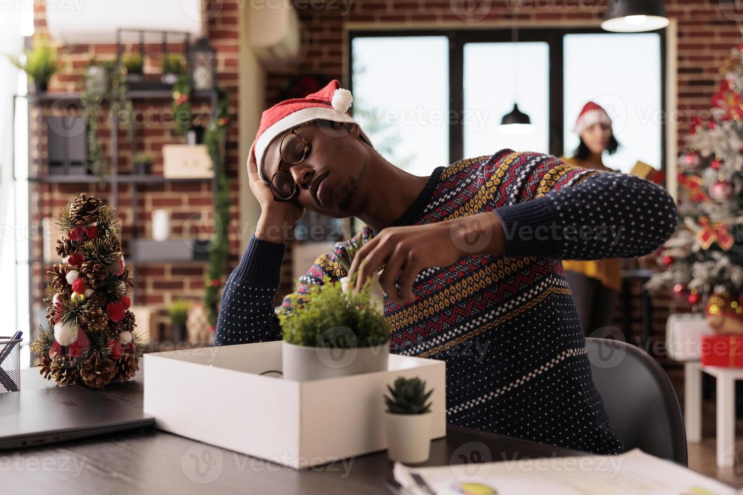 Sad depressed african american man experiencing job failure dismissed from work during holiday season. Unhappy worker packing office belongings after getting fired on xmas eve photo