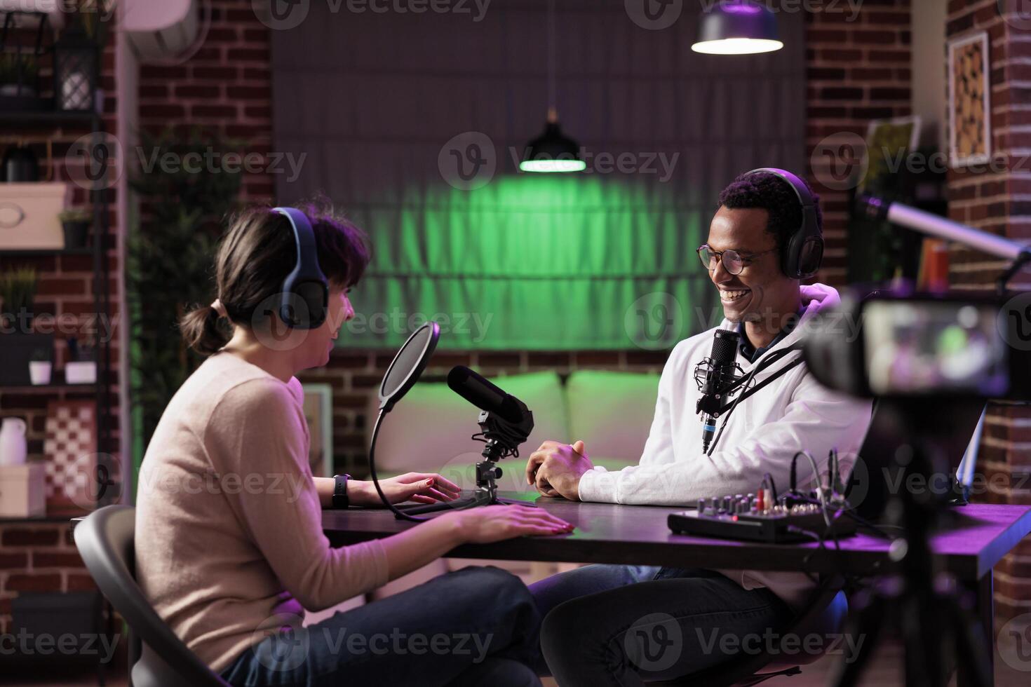 Online show host speaking with guest during live broadcast for social media website, laughing together. Internet influencer using professional tools to record podcast, streaming it on internet photo