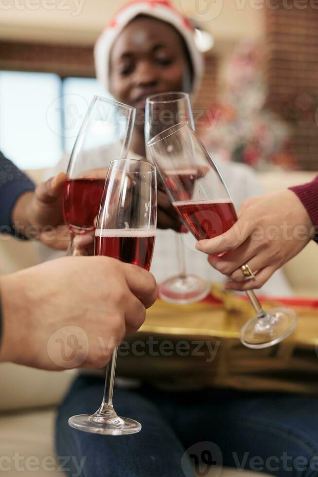 Coworkers celebrating christmas in office and clinking glasses of sparkling wine closeup. Cheerful company employees hands holding alcohol drink and toasting to new year holiday photo