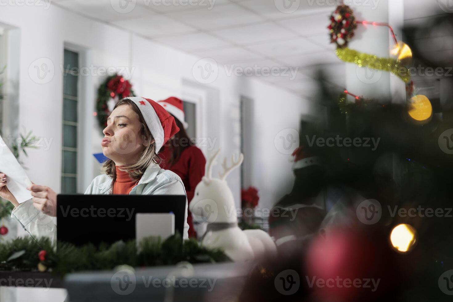 Tired unhappy employee overwhelmed by stressful difficult paperwork in xmas decorated office. Businesswoman suffering from burnout working on demanding company project during Christmas festive season photo