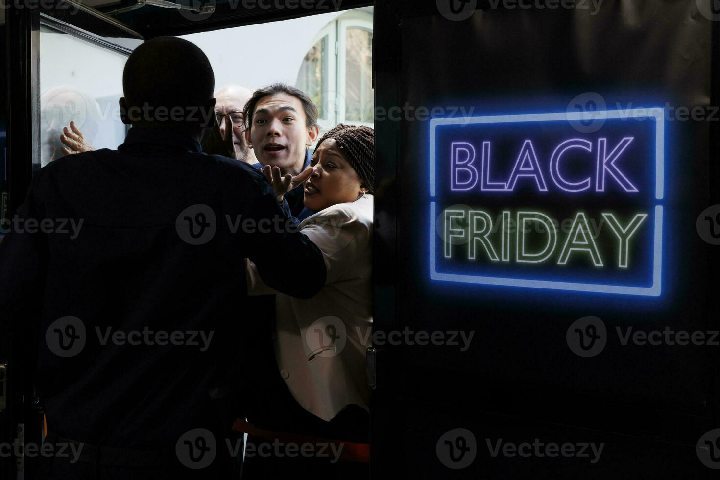 People going crazy for Black Friday deals. Shopping mall security officer managing crowd control, pushing back anxious mad shoppers trying to break into retail store before it opens photo