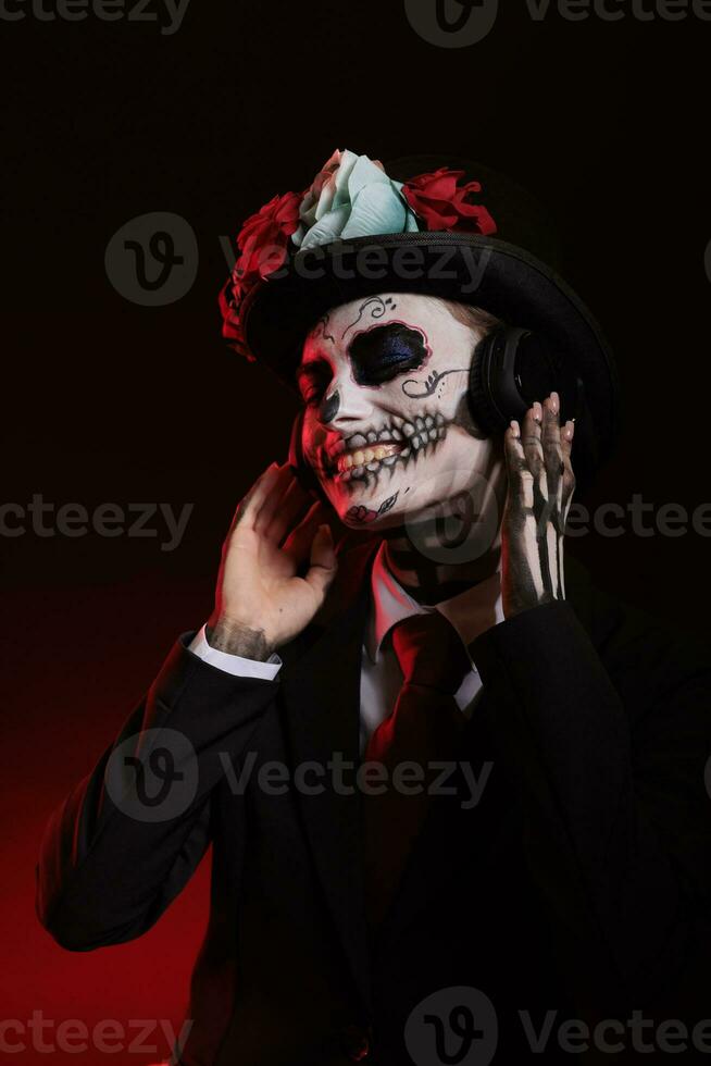 Woman in goddess of death costume listening to music on headphones, enjoying song on audio headset. Wearing santa muerte skull make up to celebrate day of the dead halloween tradition. photo