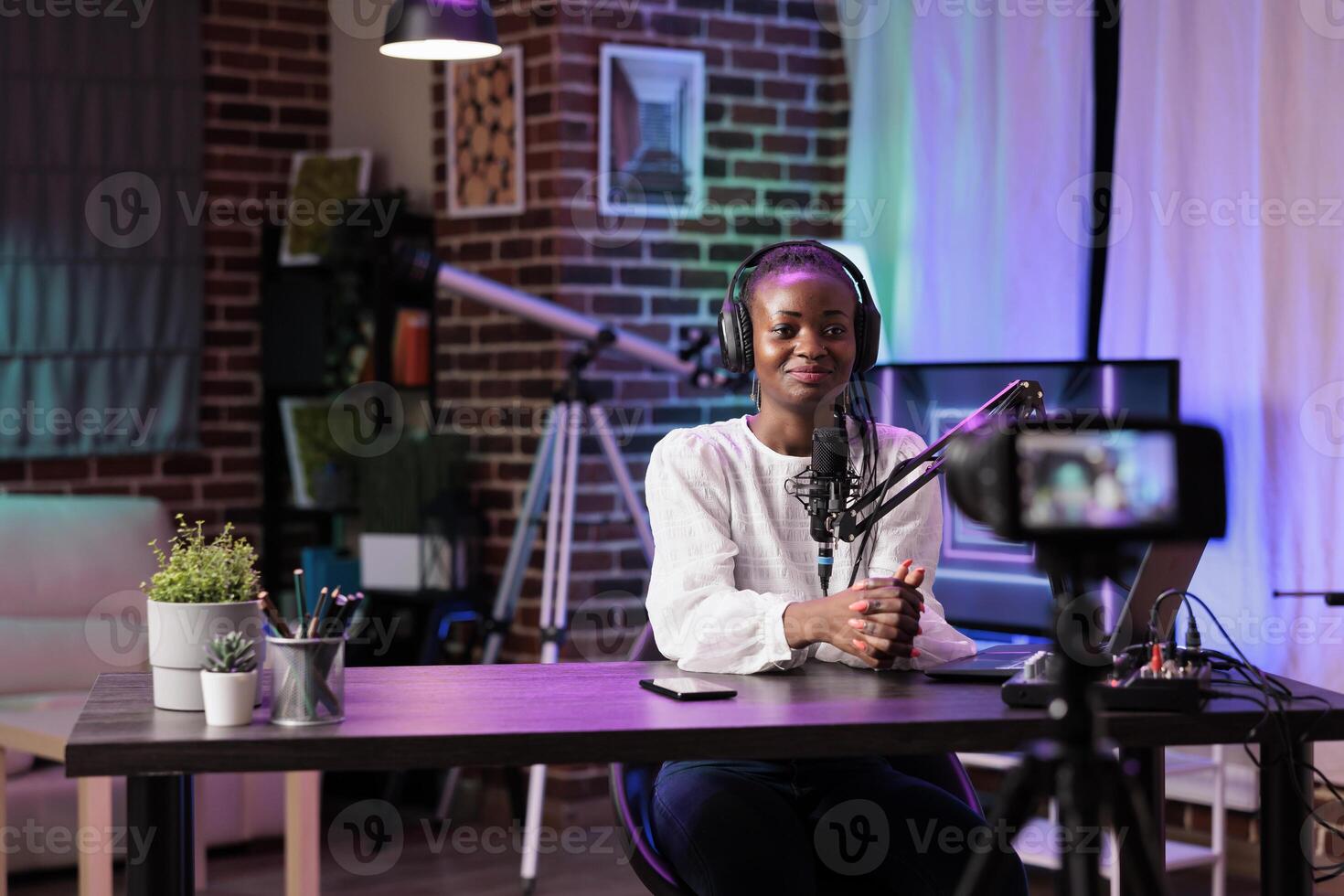 African american vlogger recording internet show using modern camera, talking about history subjects. Influencer filming live broadcast using professional devices in living room studio photo