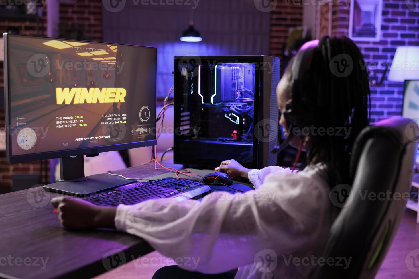 Gamer feeling relieved after finally winning last spaceship videogame mission, defeating final boss villain. African american woman playing on electronic gaming system in neon lights adorn home photo