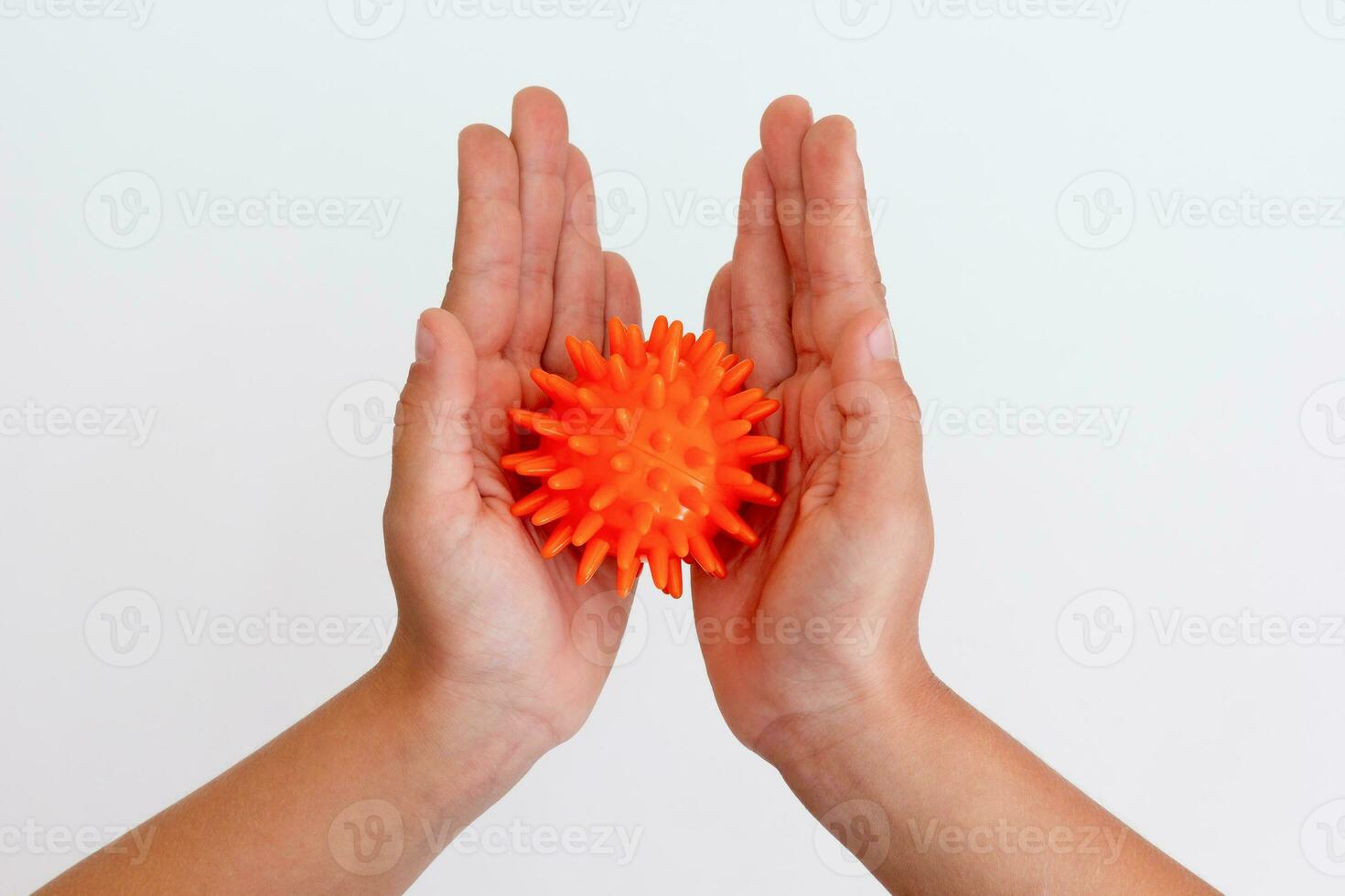 Child hands holding orange spiky ball for massage photo