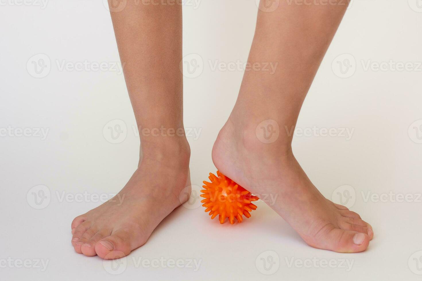 Cropped child legs doing exercises with spiky needle ball photo