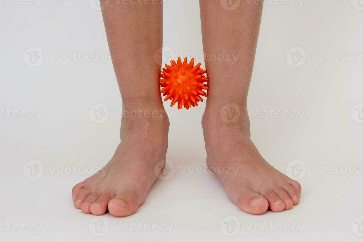 Cropped child legs doing exercises with spiky needle ball photo