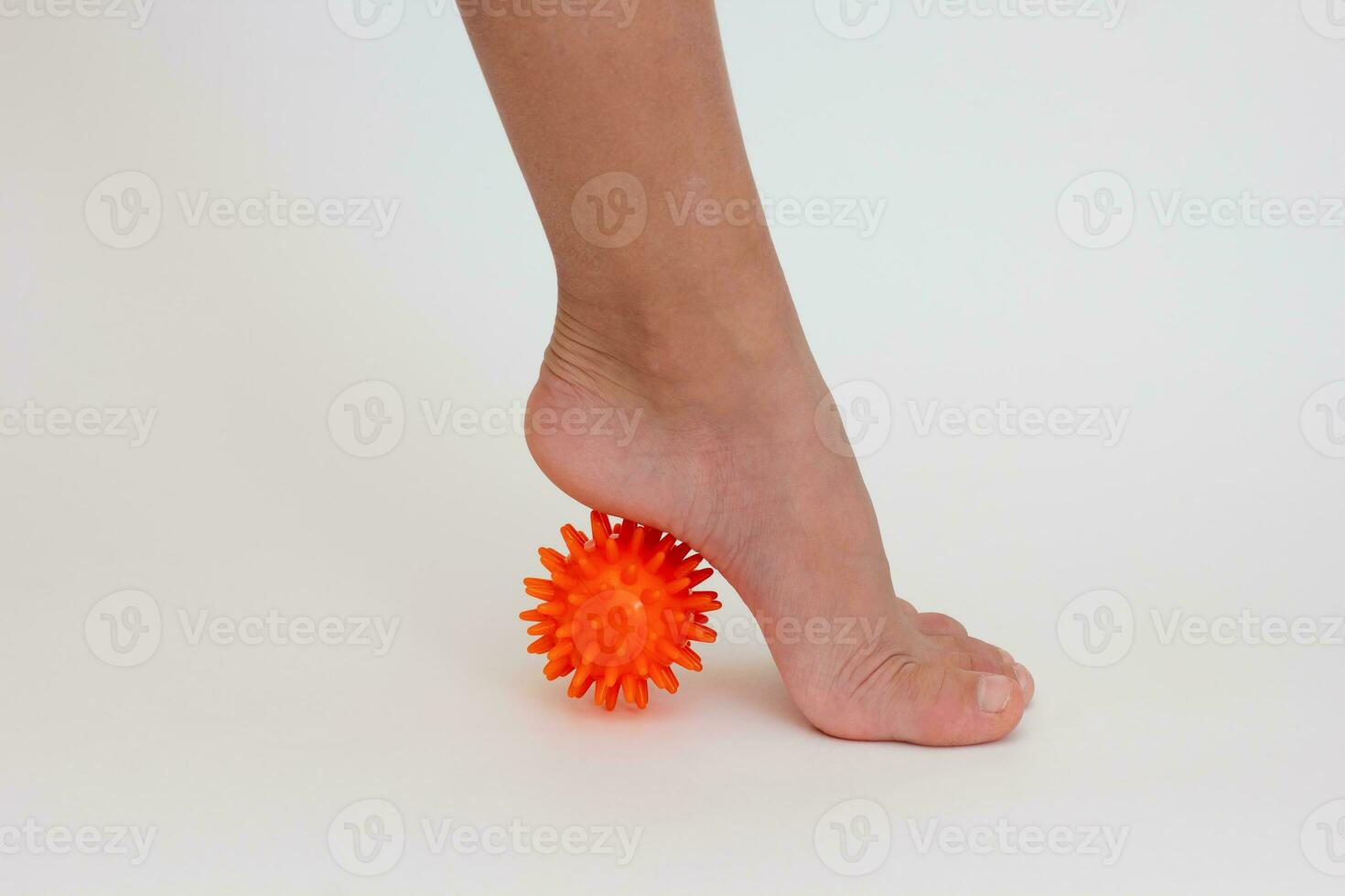 Cropped child leg doing exercises with spiky needle ball photo