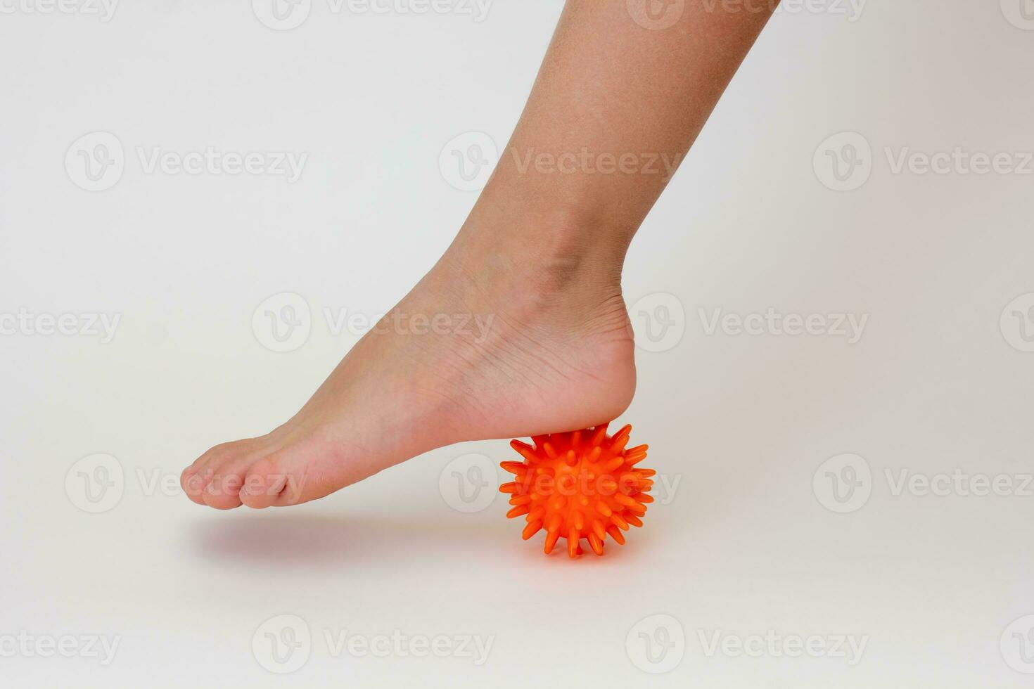 Cropped child leg doing exercises with spiky needle ball photo