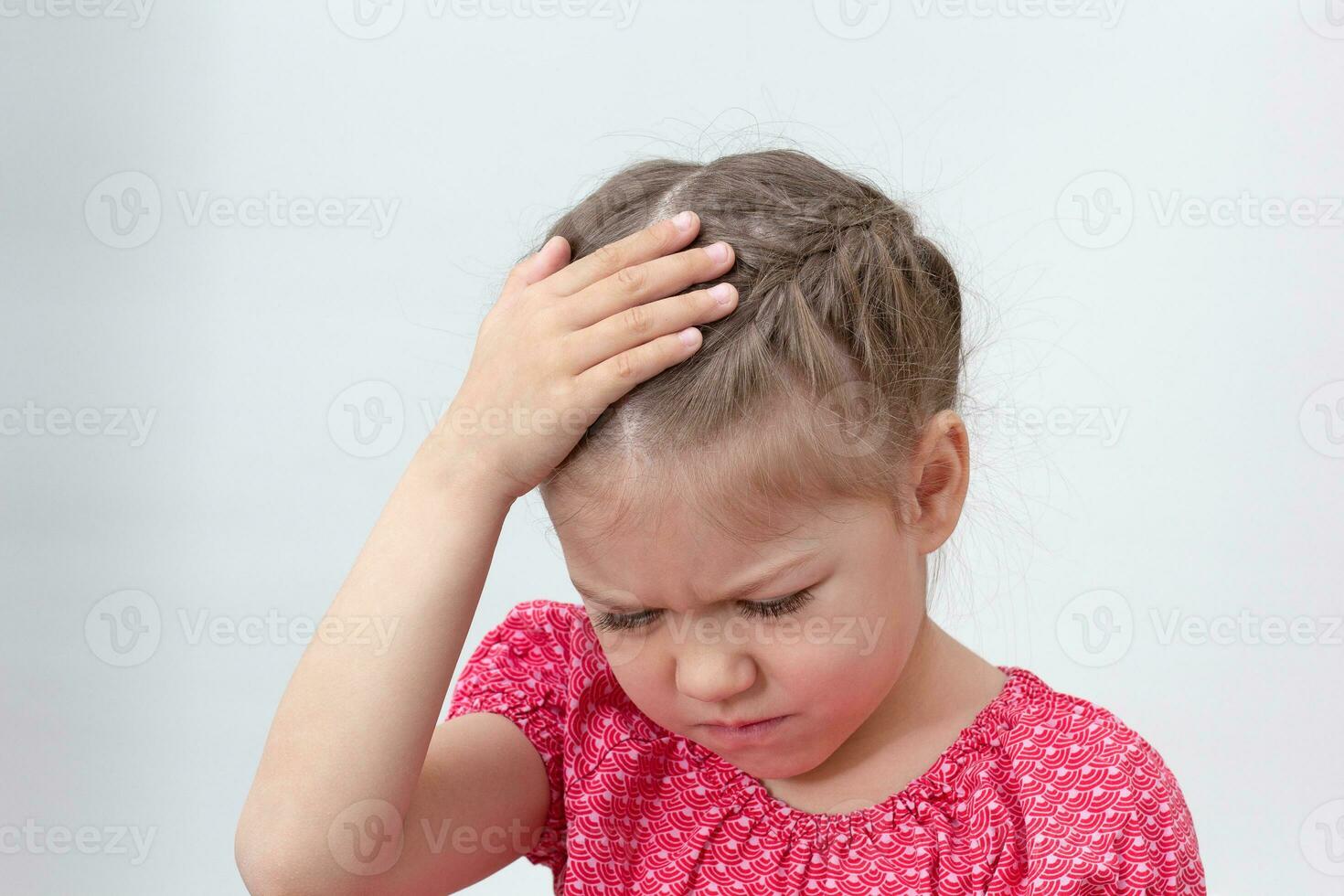 Child with headache holding hand on head photo
