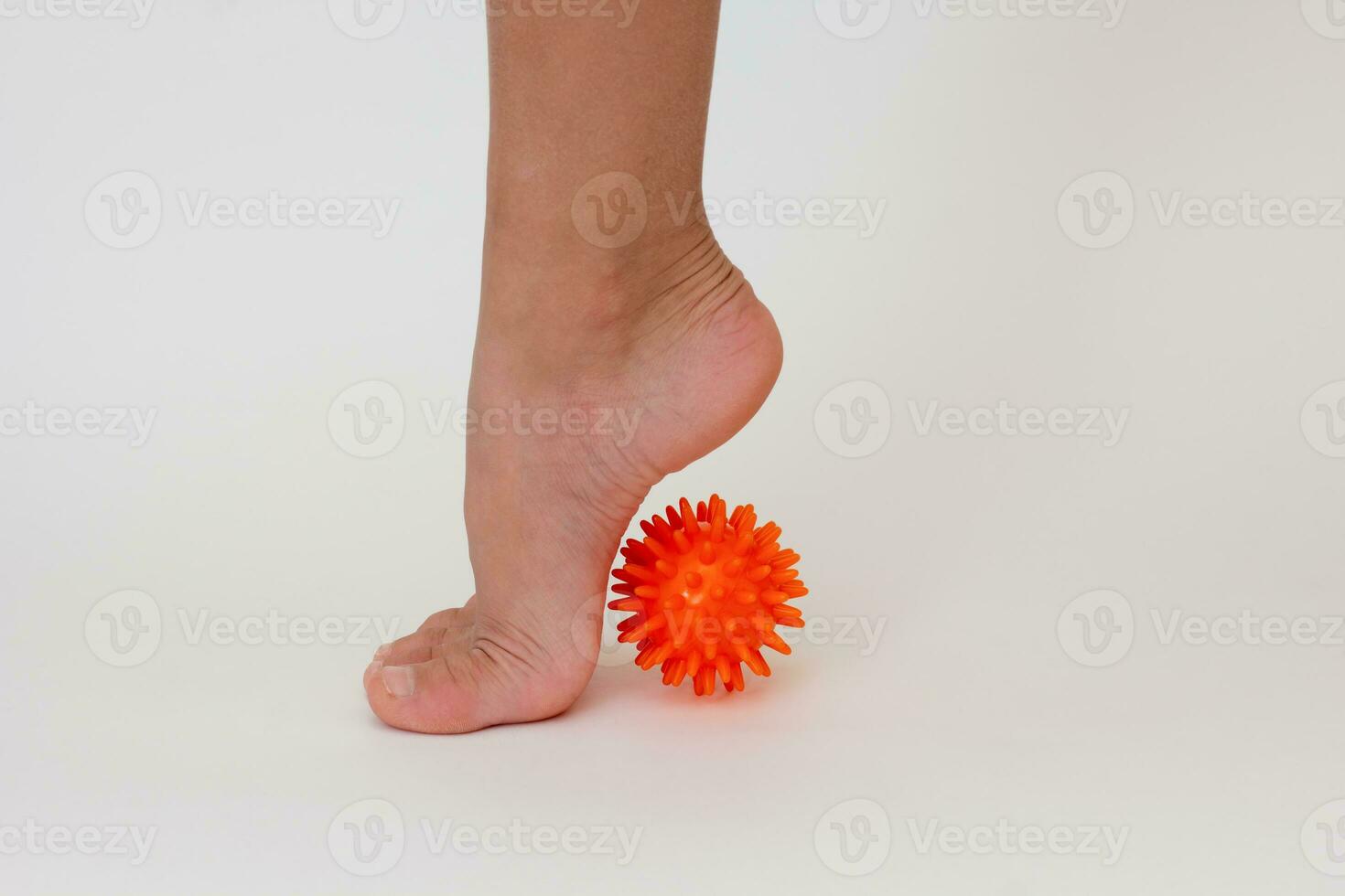 Cropped child leg doing exercises with spiky needle ball photo