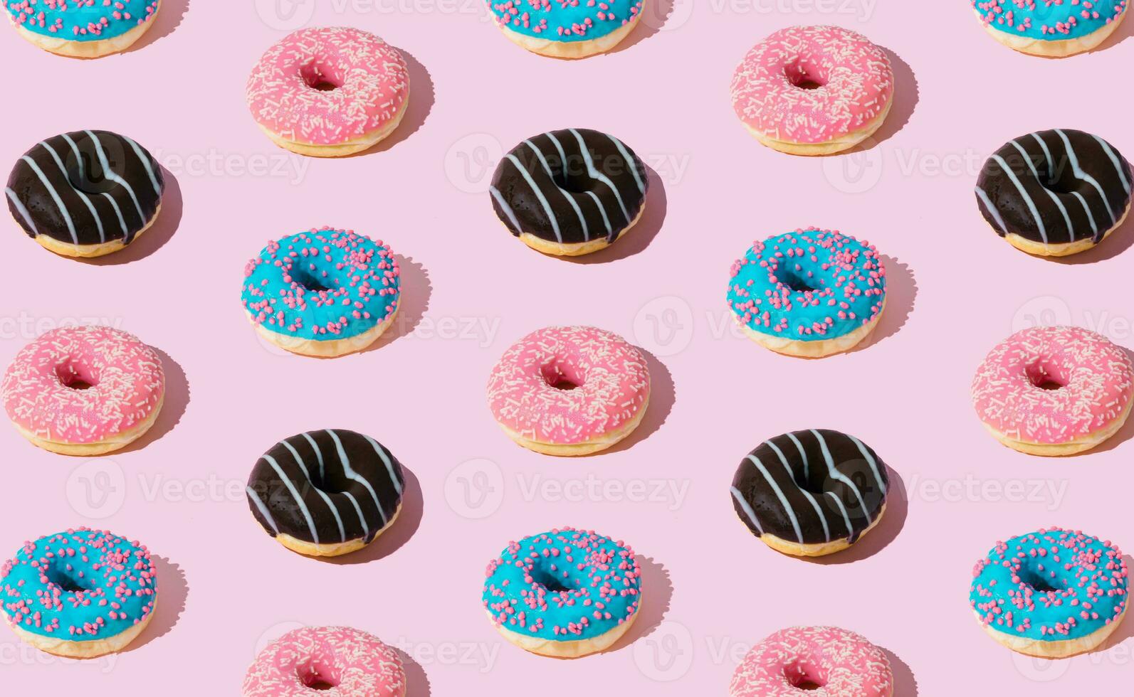 Creative pattern of colorful donuts on pastel pink background. Minimal concept. Trendy donuts pattern. Yummy food composition. Donuts aesthetic background. photo
