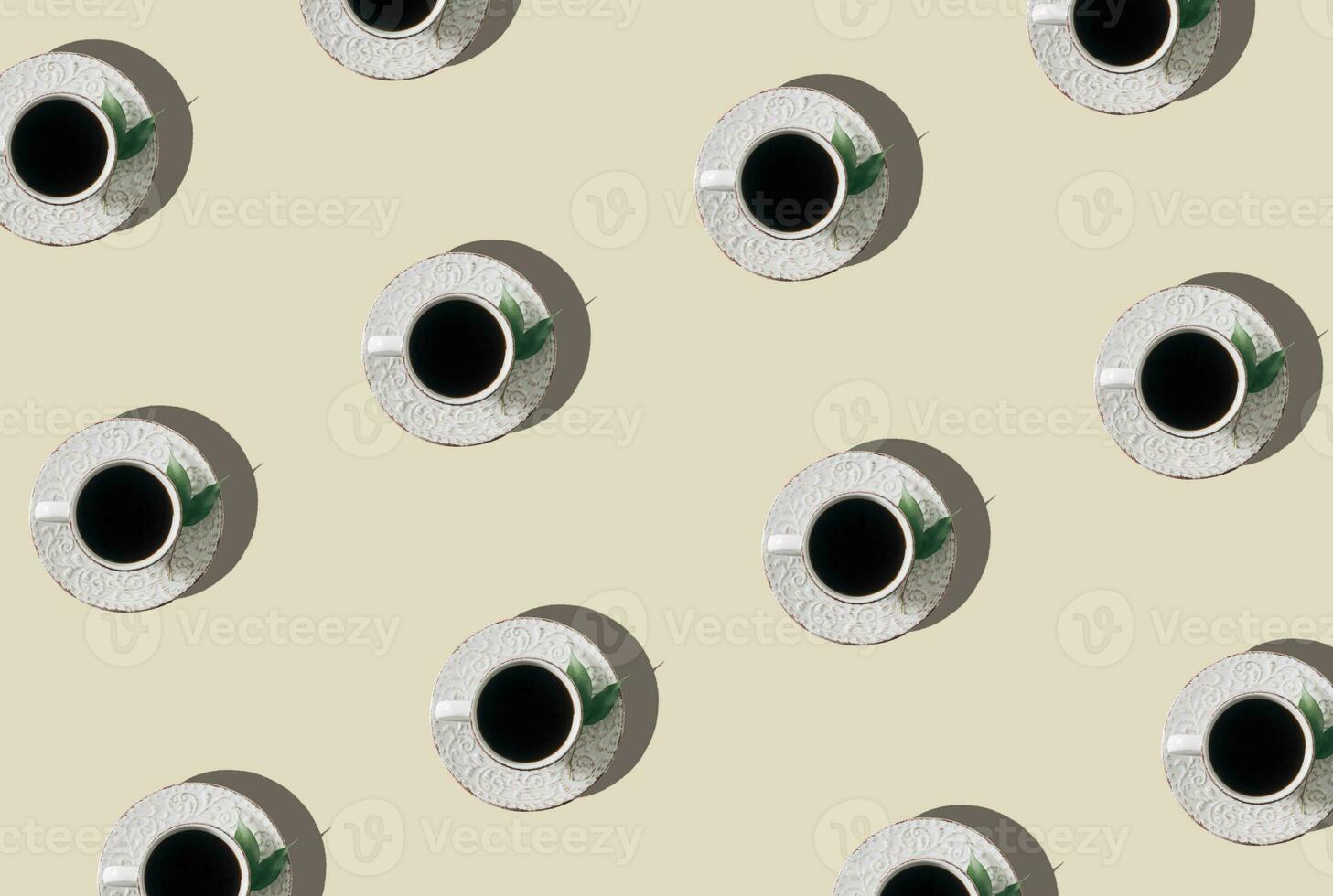 Trendy pattern composition made of white cup of coffee decorated with green leaves on light cream background. Creative coffee concept. Minimal pattern idea. Coffee aesthetic background. Flat lay. photo