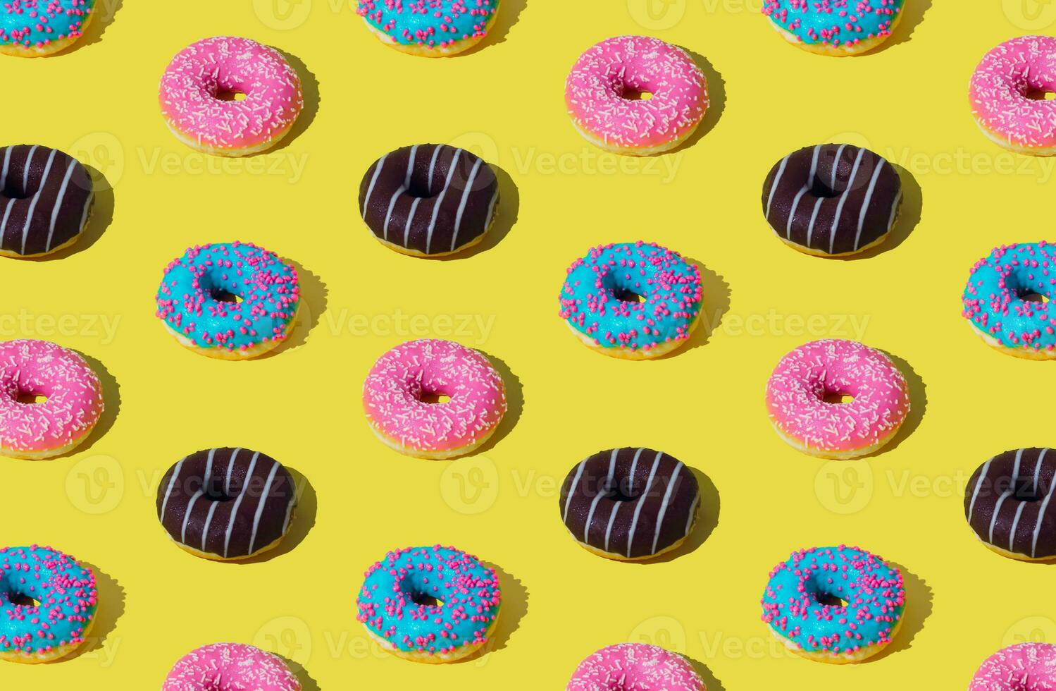 Creative pattern of colorful donuts on light yellow background. Minimal concept. Trendy donuts pattern background. Yummy food composition. Donuts aesthetic. photo