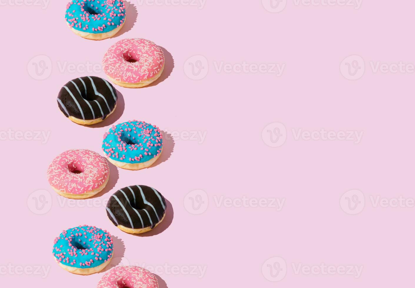 Creative arrangement of colorful donuts on pastel pink background with copy space. Minimal food concept. Trendy yummy donuts idea. Donuts aesthetic background. photo