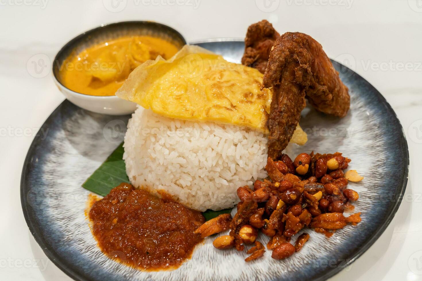 Asian food Nasi Lemak is a rice dish infused with coconut milk. Served with sambal, fried chicken wing, fried peanut, fried egg with curry sauce. photo