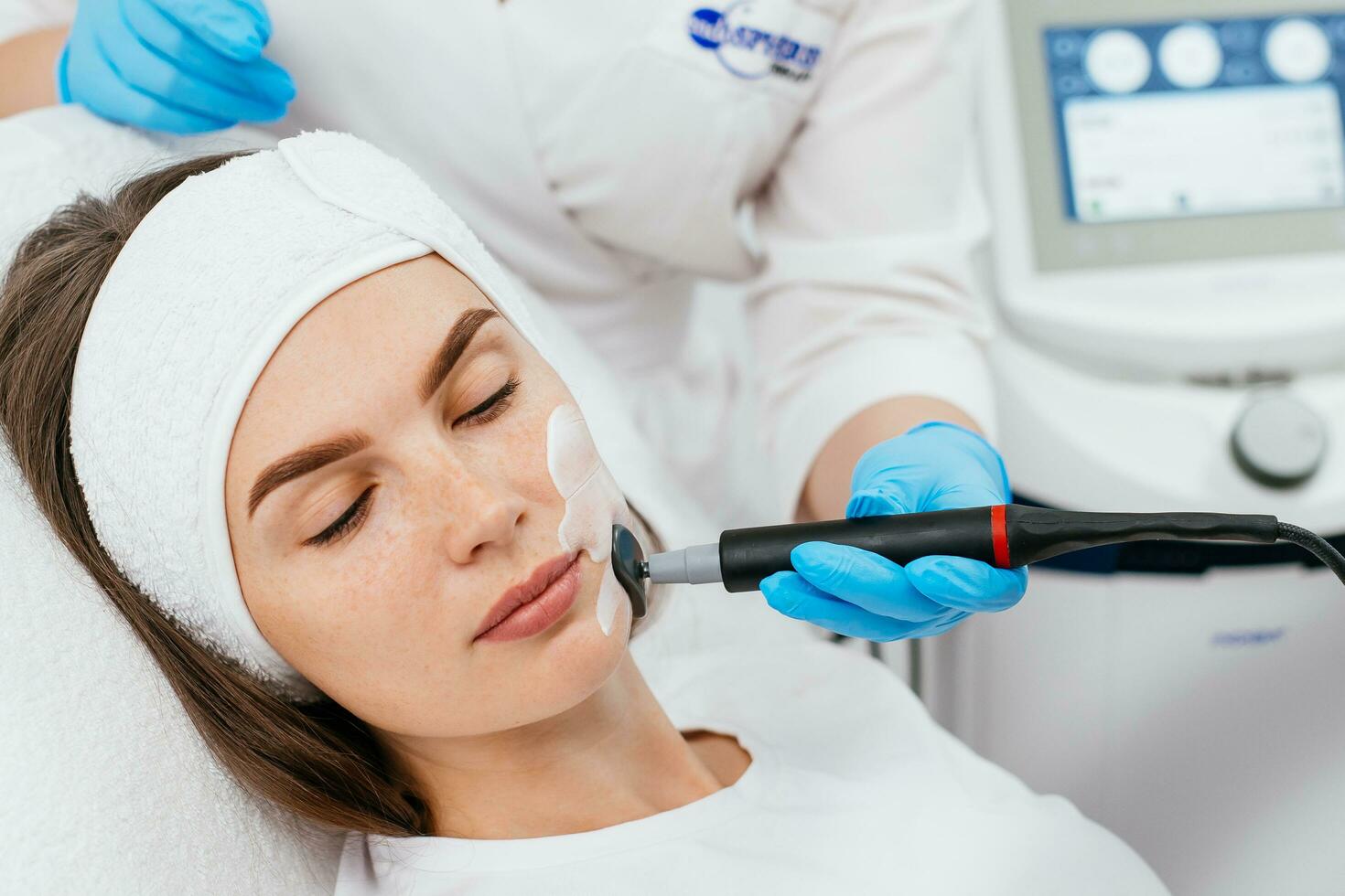 Professional female cosmetologist doing hydra-facial procedure in cosmetology clinic. Doctor using hydra vacuum cleaner. Rejuvenation and cosmetology concept photo