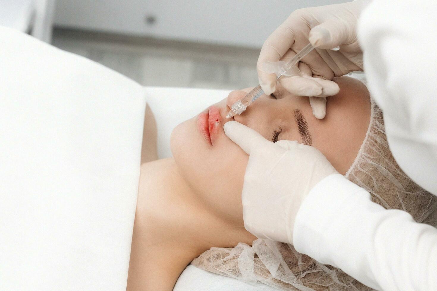 close-up, female lips. Surgeon, in medical gloves, carefully and slowly injects hyaluronic acid into woman's lips with a syringe. lip augmentation procedure. beauty injections. Plastic surgery. photo