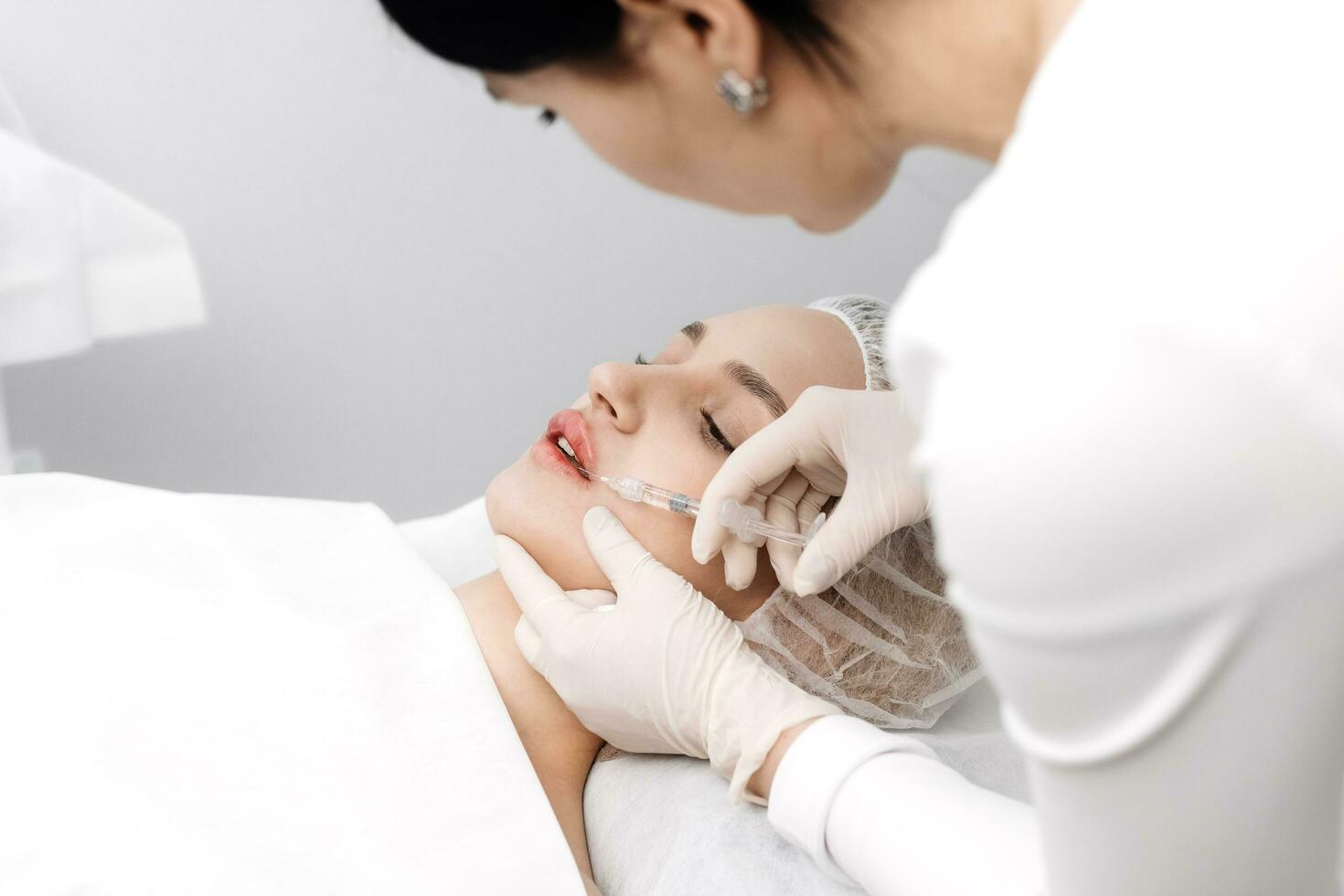 de cerca, hembra labios. cirujano, en médico guantes, cuidadosamente y despacio inyecta hialurónico ácido dentro mujer labios con un jeringuilla. labio aumento procedimiento. belleza inyecciones el plastico cirugía. foto