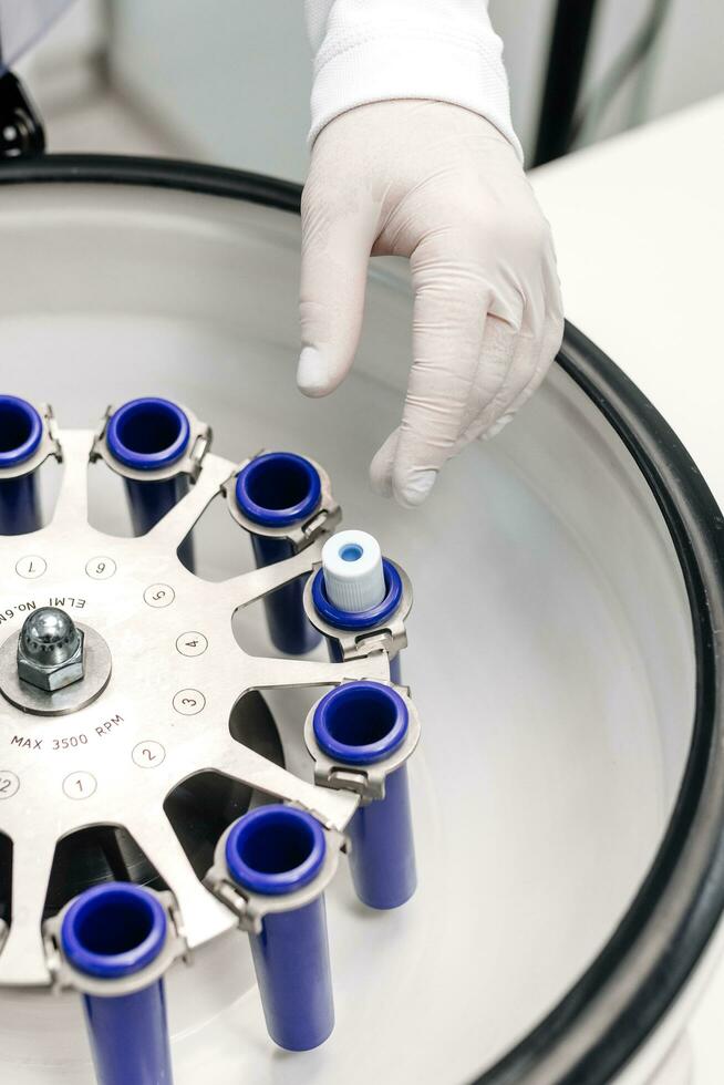 Cosmetologist extracting blood plasma using a centrifuge. The doctor takes out tubes with blood plasma. photo