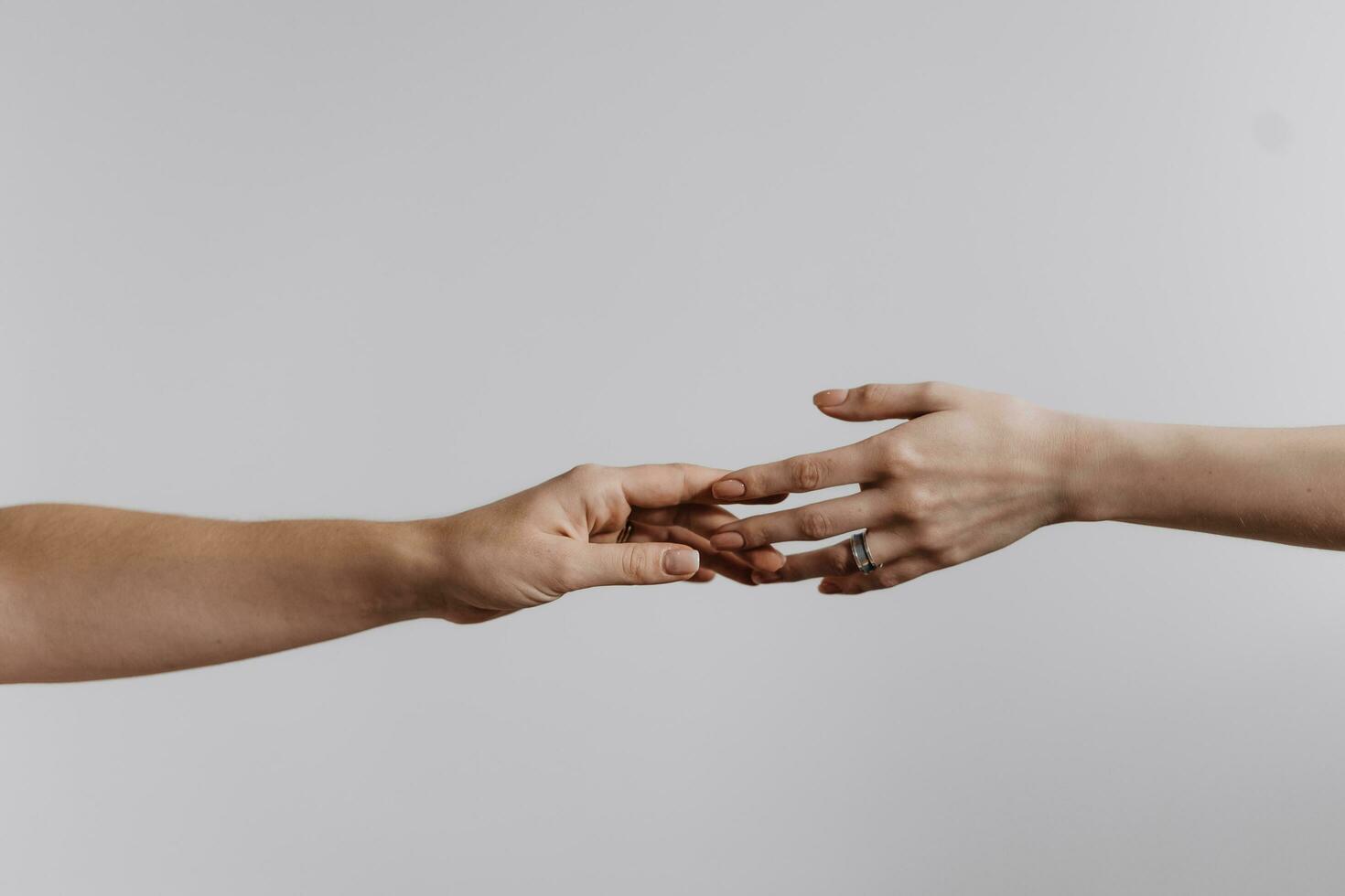 Hands touching each other isolated on grey background. Concept of human relation, community, togetherness, teamwork, love, symbolism, culture and history. photo