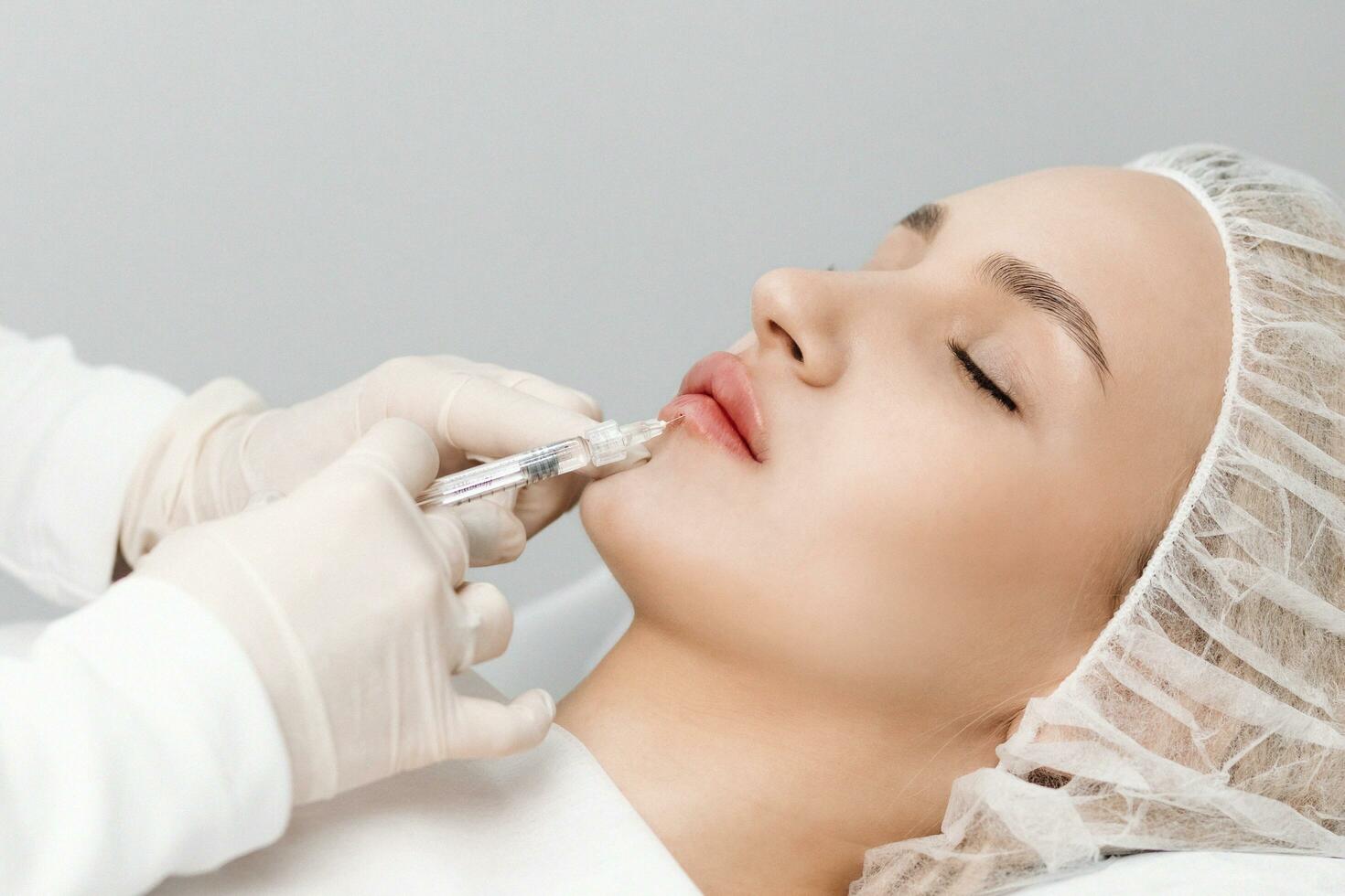 close-up, female lips. Surgeon, in medical gloves, carefully and slowly injects hyaluronic acid into woman's lips with a syringe. lip augmentation procedure. beauty injections. Plastic surgery. photo