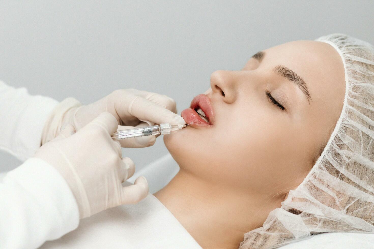 close-up, female lips. Surgeon, in medical gloves, carefully and slowly injects hyaluronic acid into woman's lips with a syringe. lip augmentation procedure. beauty injections. Plastic surgery. photo